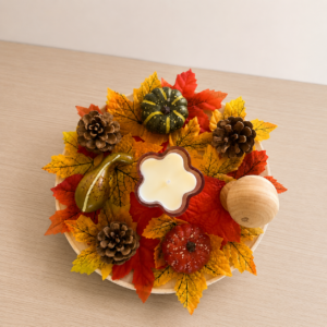 Centre de table automnal fait main avec feuilles, pommes de pin, courges et bougie